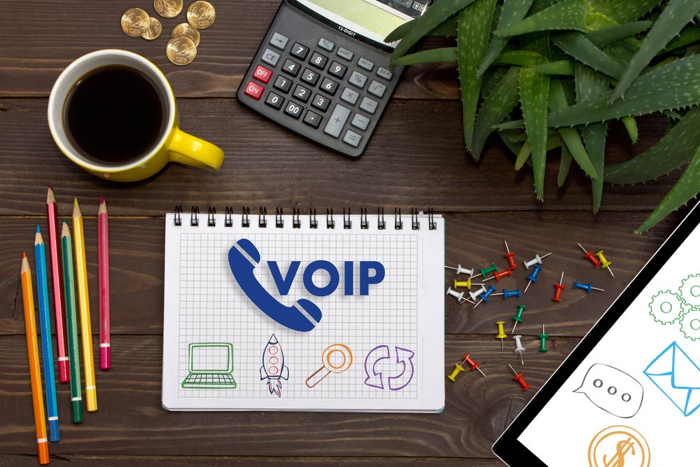 VOIP on notebook with coffee, calculator, and colored pencils