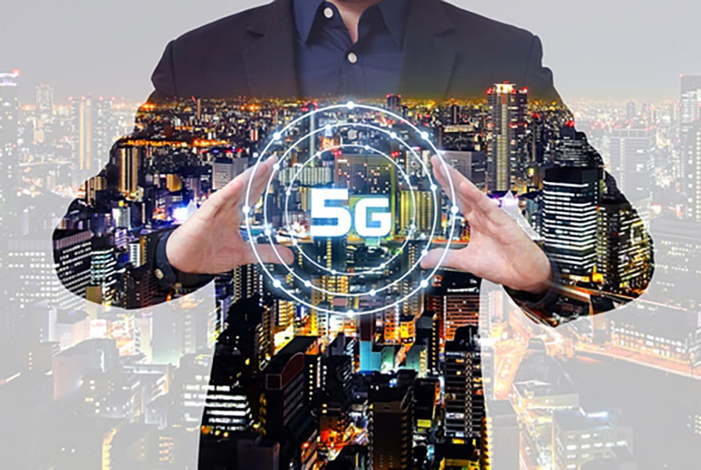 Man in suit framing 5G icon with city landscape