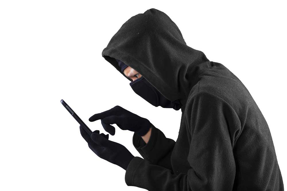 thief in black hoodie using phone