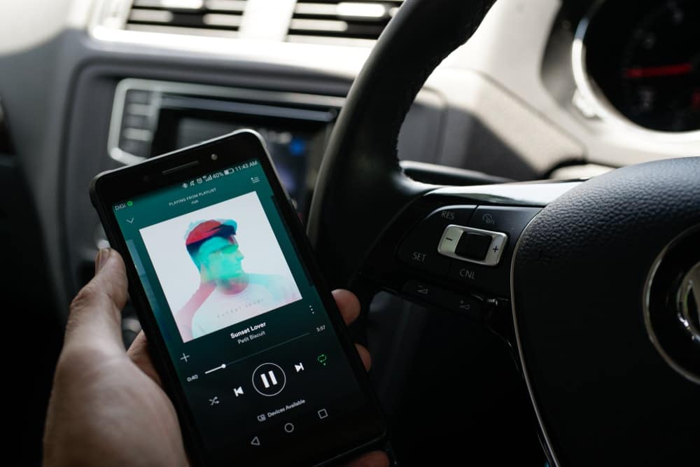 person holding phone with Spotify in car