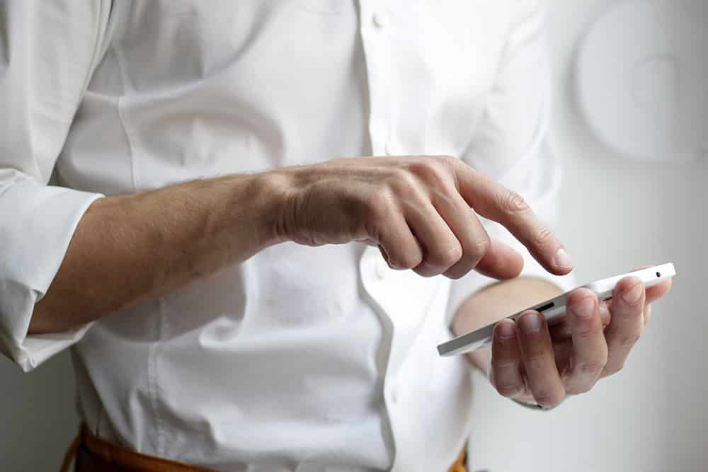 man in white shirt using his smartphone