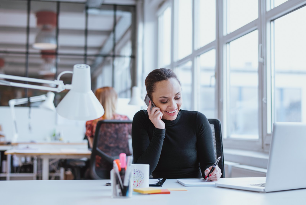 Woman speaking on phone and writing down notes