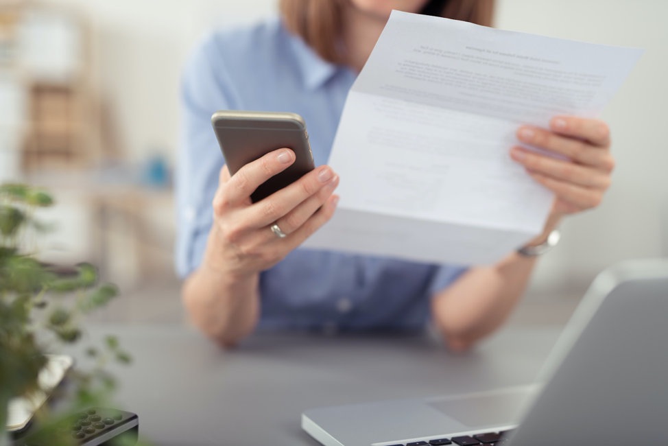 woman holding cell phone and letter